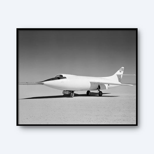 A black and white photo showcases the D-558-II Skyrocket Aircraft | X Planes, a marvel in aviation history, parked on a flat, barren expanse. The sleek, streamlined aircraft, with no visible markings on its fuselage and a single tail fin, is illuminated by sunlight under a clear sky—an emblem of the supersonic flight era.