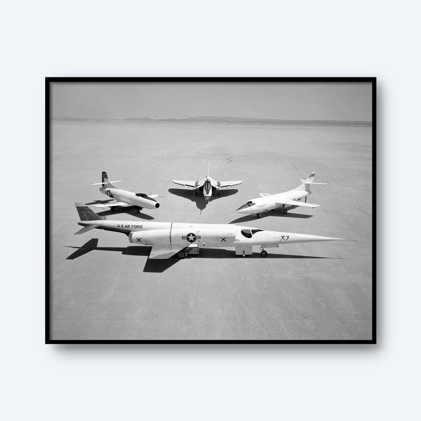 A black and white photograph titled "Group Photo of Douglas Aircraft Company Airplanes | X Planes" showcasing three experimental X-planes on a vast, flat desert surface. In the foreground is a sleek jet labeled "U.S. Air Force" with an "X" on its tail, symbolizing aviation history. Behind it, two smaller aircraft from the Douglas Aircraft Company are positioned in a triangle formation.
