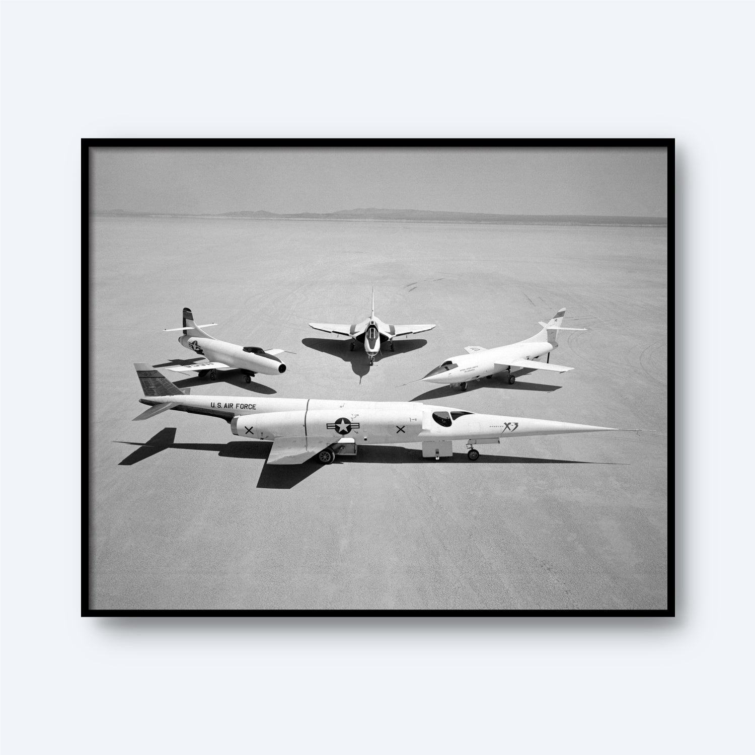 A black and white photograph titled "Group Photo of Douglas Aircraft Company Airplanes | X Planes" showcasing three experimental X-planes on a vast, flat desert surface. In the foreground is a sleek jet labeled "U.S. Air Force" with an "X" on its tail, symbolizing aviation history. Behind it, two smaller aircraft from the Douglas Aircraft Company are positioned in a triangle formation.