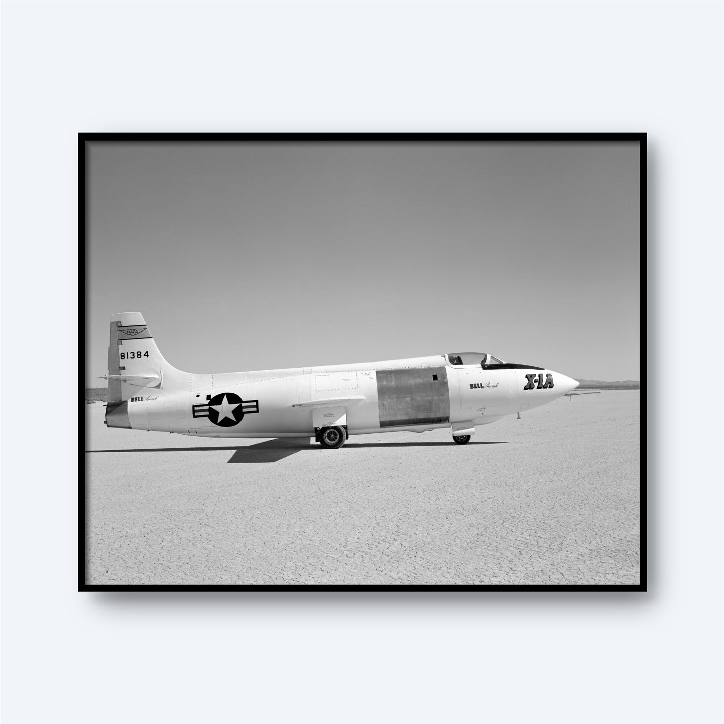 A black and white photograph of the X-1A Aircraft with Unpainted Fuselage Print from X Planes, depicting the aircraft on a flat, barren surface. The unpainted fuselage bears the number 606384 on its tail and a star emblem with stripes on its side. The text "Bell XS-1" and "the Glamorous Glennis" are visible, marking an era of supersonic flight.