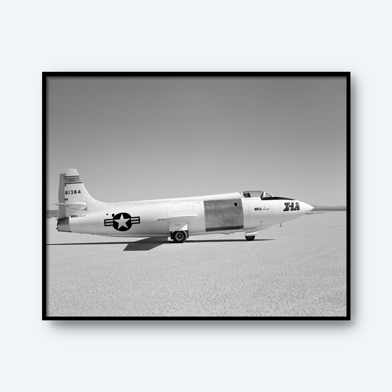A black and white photograph of the X-1A Aircraft with Unpainted Fuselage Print from X Planes, depicting the aircraft on a flat, barren surface. The unpainted fuselage bears the number 606384 on its tail and a star emblem with stripes on its side. The text "Bell XS-1" and "the Glamorous Glennis" are visible, marking an era of supersonic flight.