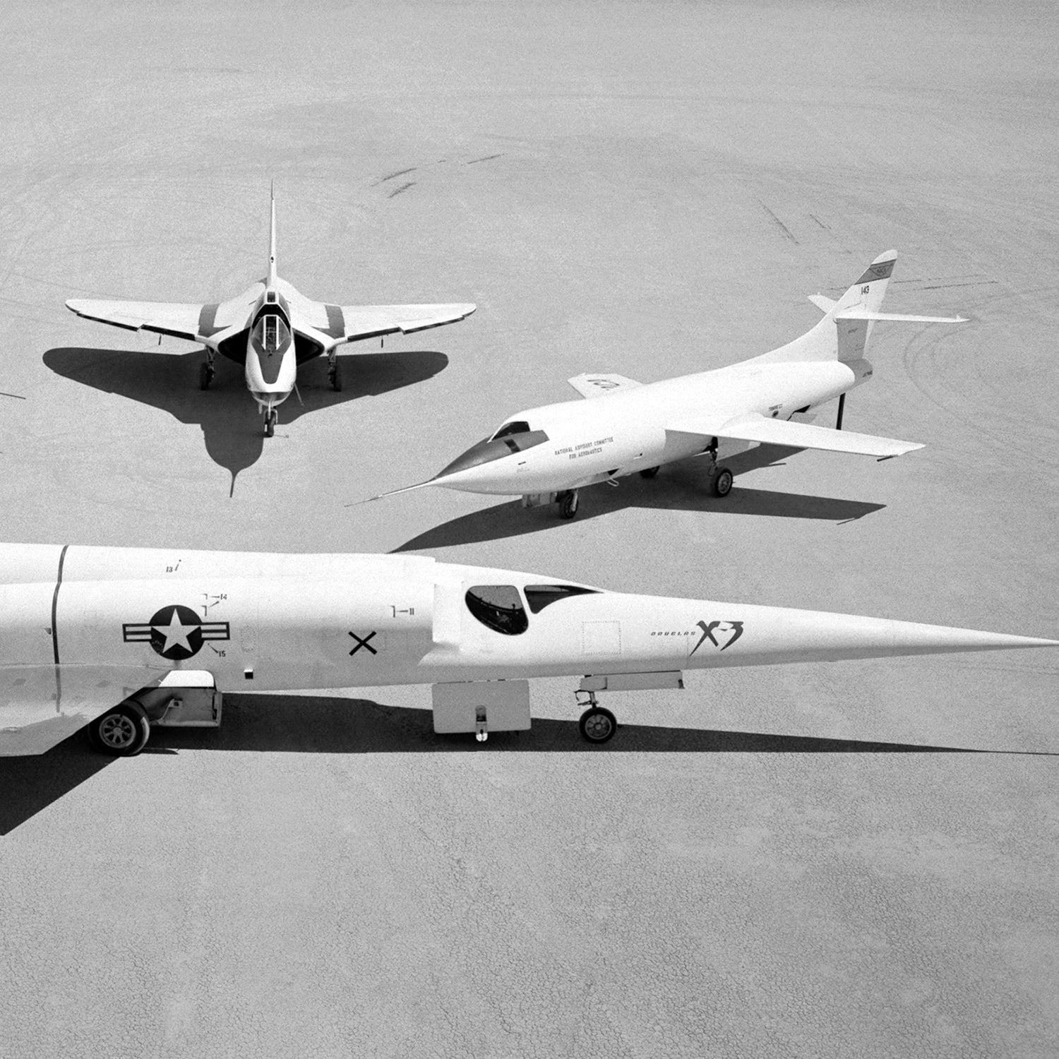 Black-and-white image of three military aircraft positioned on a flat surface. In front is an X-3 jet with a long, pointed nose, representing the pinnacle of experimental X-planes. Behind it to the right stands the smaller Douglas D-558-2 Skyrocket from the renowned Douglas Aircraft Company. To the left is a Phantom II featuring upward-tilted wings. Titled "Group Photo of Douglas Aircraft Company Airplanes | X Planes.
