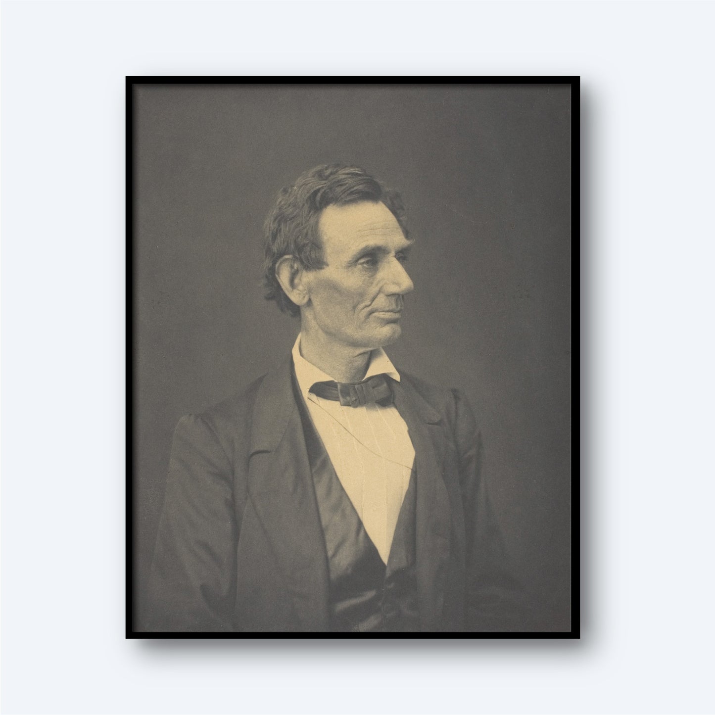 The "Abraham Lincoln by Alexander Hesler" photograph features a black-and-white portrait of a man with short, dark hair, dressed in a suit with a bow tie. He faces slightly to the left with a thoughtful expression. The portrait, distinguished by its gravitas akin to an Abraham Lincoln portrayal, is framed in black and set against a neutral background.