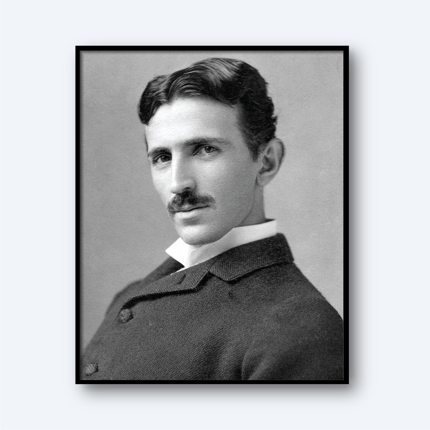 The Nikola Tesla Print features a black-and-white portrait of Tesla with wavy dark hair and a mustache, dressed in a suit with a white collar. He is turned slightly to the side and gazes directly at the camera with a serious expression. The neutral, light gray background enhances the image, reflecting his era of modern electricity.