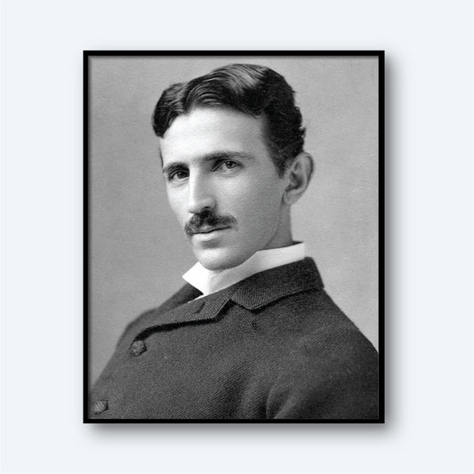 The Nikola Tesla Print features a black-and-white portrait of Tesla with wavy dark hair and a mustache, dressed in a suit with a white collar. He is turned slightly to the side and gazes directly at the camera with a serious expression. The neutral, light gray background enhances the image, reflecting his era of modern electricity.