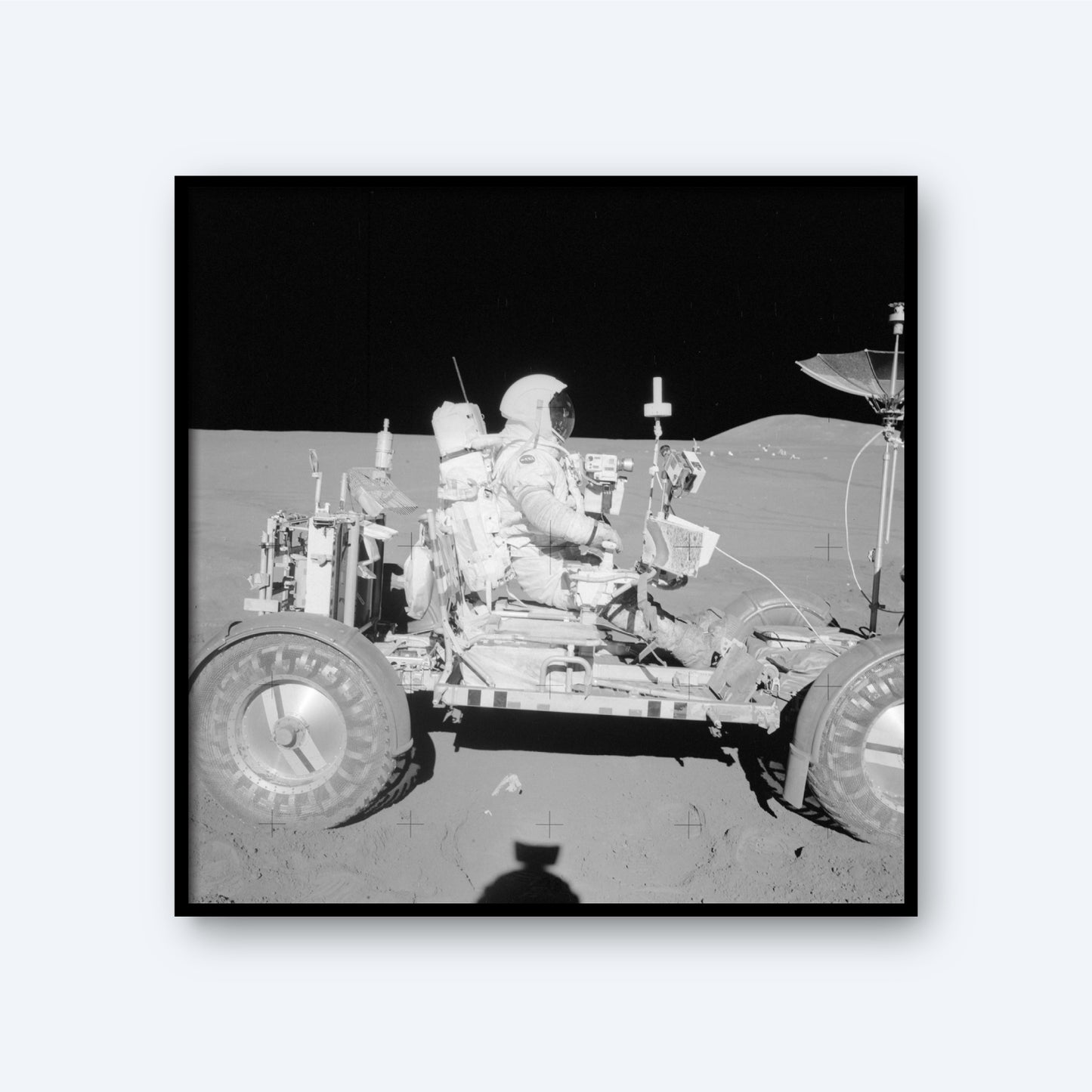 The NASA Apollo 15 Astronaut in the Lunar Rover on The Moon features an astronaut in a spacesuit seated on the Lunar Rover against the backdrop of the lunar landscape, capturing an iconic moment in space history. The rover is equipped with various instruments and antennas, with the shadow of the photographer visible in the foreground.