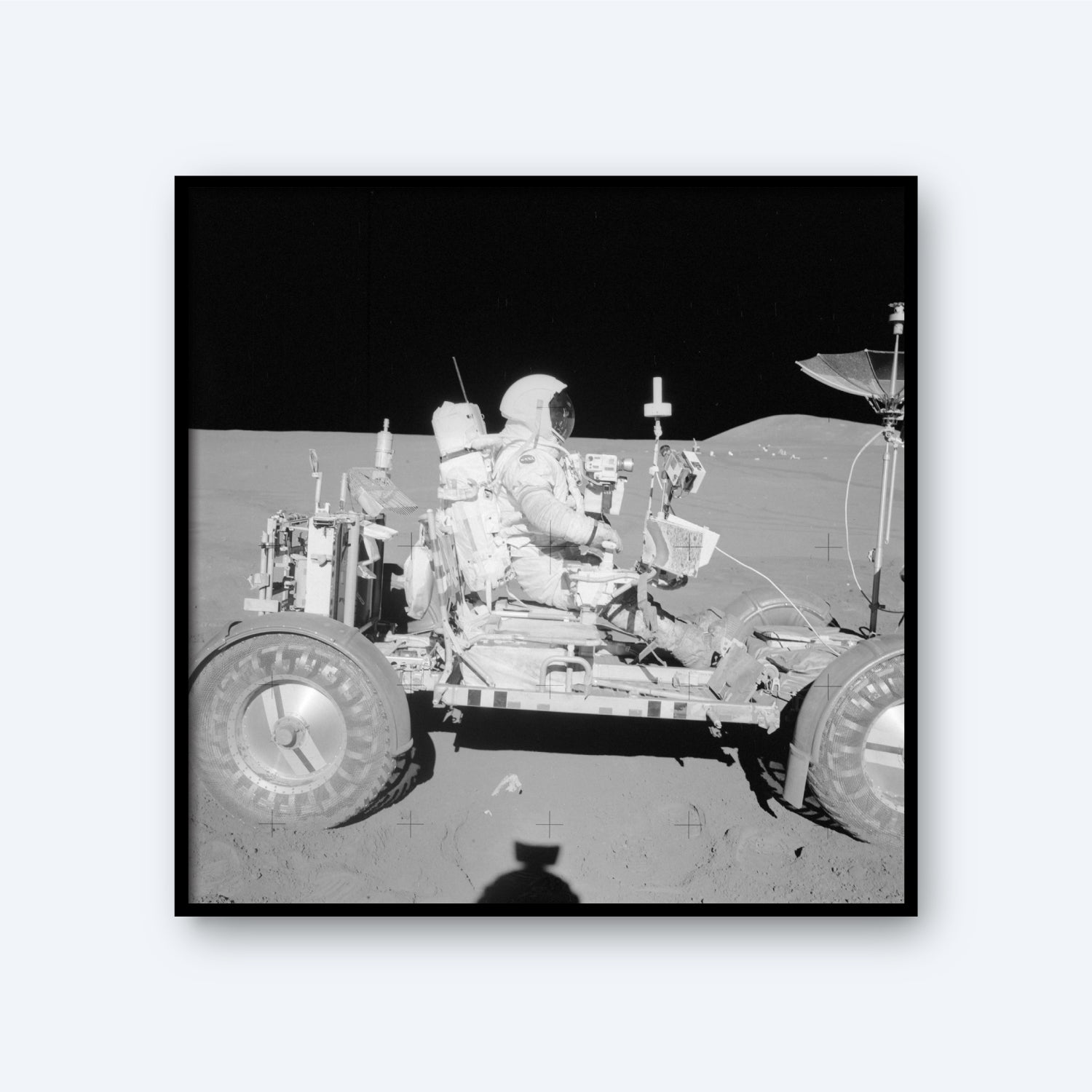 The NASA Apollo 15 Astronaut in the Lunar Rover on The Moon features an astronaut in a spacesuit seated on the Lunar Rover against the backdrop of the lunar landscape, capturing an iconic moment in space history. The rover is equipped with various instruments and antennas, with the shadow of the photographer visible in the foreground.