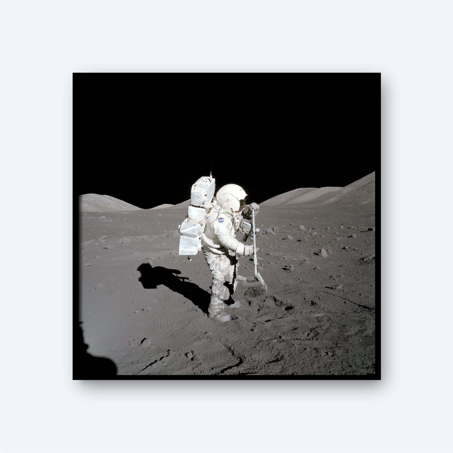 An astronaut in a bulky spacesuit is collecting samples on the lunar surface in the NASA Apollo 17 mission. The dark sky contrasts with the gray, rocky terrain, while the astronaut's shadow stretches across the ground. Lunar hills can be seen in the background, highlighting a remarkable moment in NASA's space exploration and astronomy efforts.