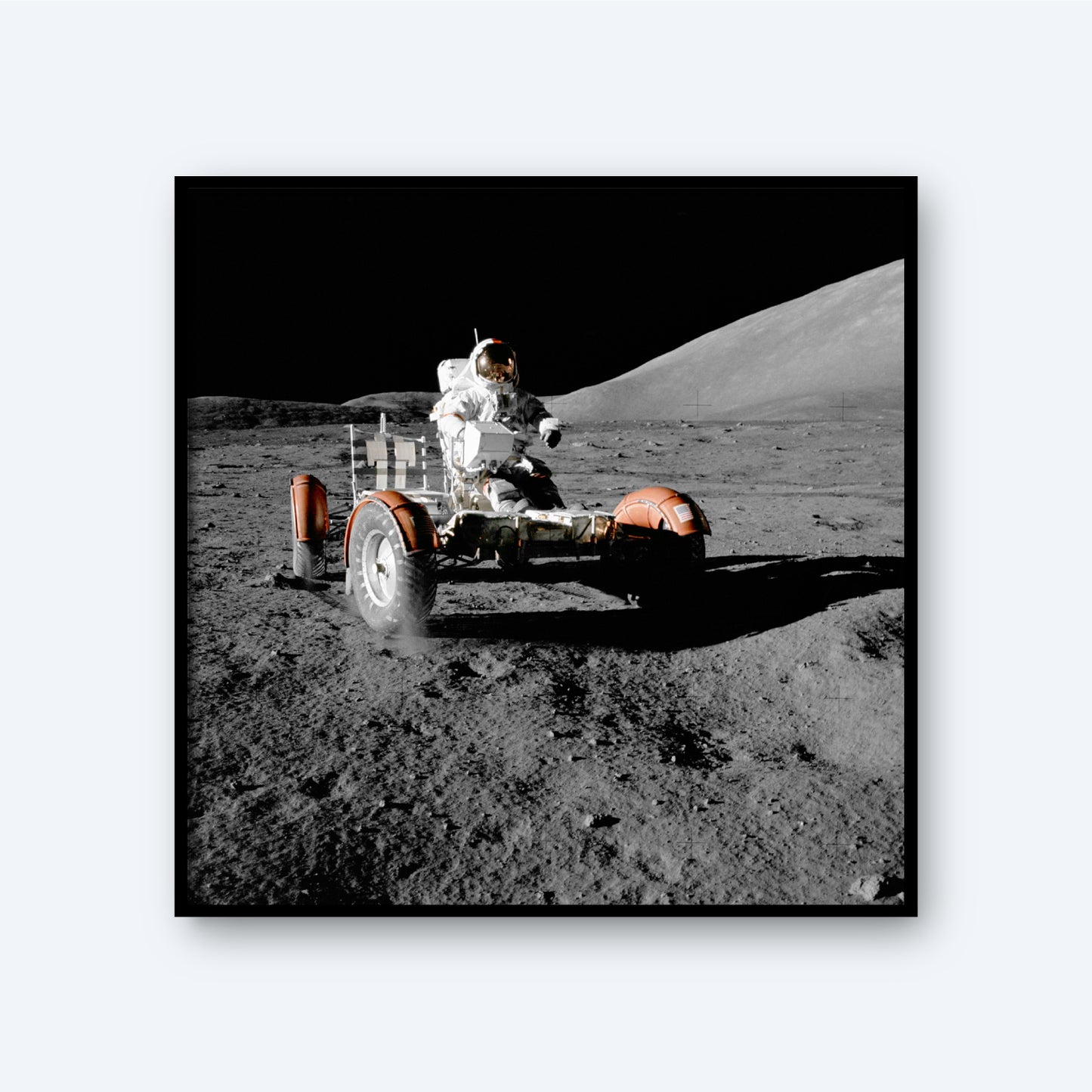 A photograph showcases the NASA Apollo 17 Lunar Rover Vehicle on the Moon, driven by an astronaut in a spacesuit across the lunar surface. The dark expanse of space and the rocky lunar landscape provide a dramatic background, embodying the spirit of space exploration as dust rises beneath the moving rover.