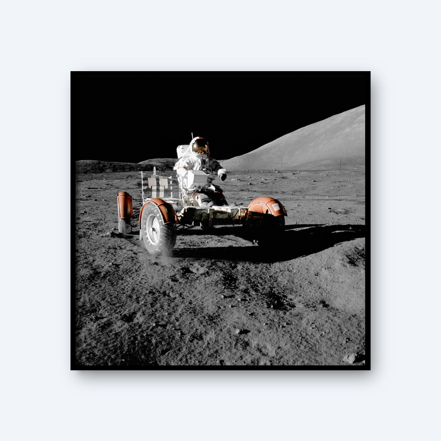 A photograph showcases the NASA Apollo 17 Lunar Rover Vehicle on the Moon, driven by an astronaut in a spacesuit across the lunar surface. The dark expanse of space and the rocky lunar landscape provide a dramatic background, embodying the spirit of space exploration as dust rises beneath the moving rover.