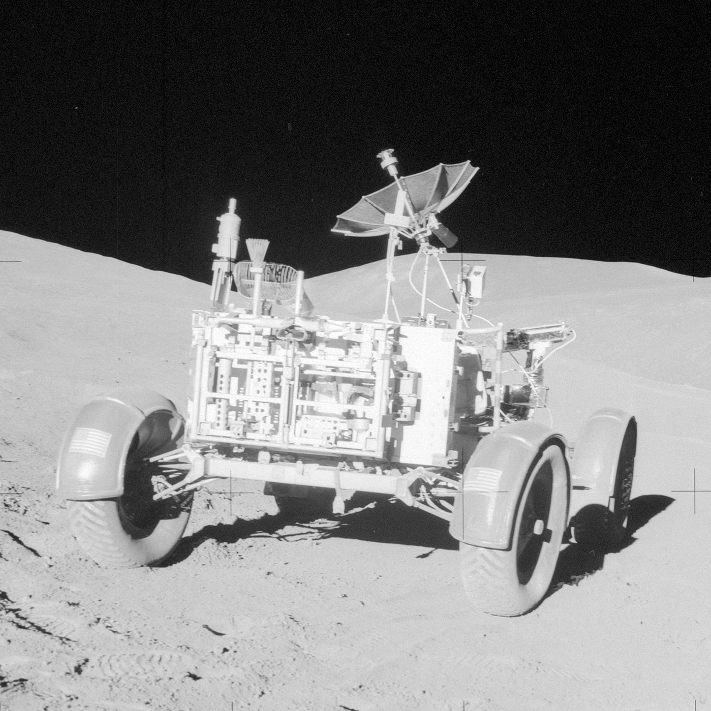 Black and white photo of the NASA Apollo Lunar Rover on The Moon, equipped with four large wheels and an antenna dish, showcasing NASA's engineering prowess. The desolate lunar landscape and blackness of space are visible in the background. Shadows and fine details of the terrain are evident.