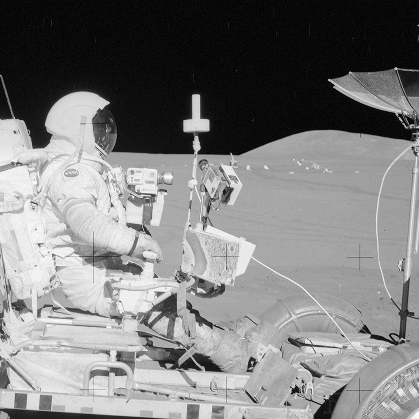 A NASA Apollo 15 Astronaut in the Lunar Rover on The Moon sits in a spacesuit, holding equipment, against the backdrop of a barren lunar landscape and an endlessly dark sky. Mounted on the rover are equipment and instruments integral to space history.
