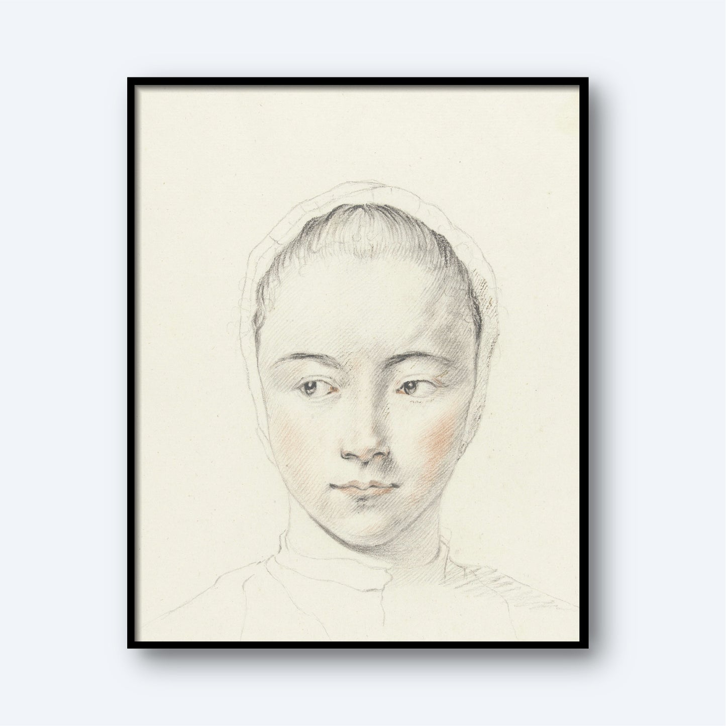 A framed sketch of a young woman with a serene expression. This delicate pencil portrait, titled *Kop van een meisje by Judith M. Testart,* features slight touches of color highlighting her cheeks. She wears a headscarf, and the plain white background makes her the focal point of this exquisite wall art.