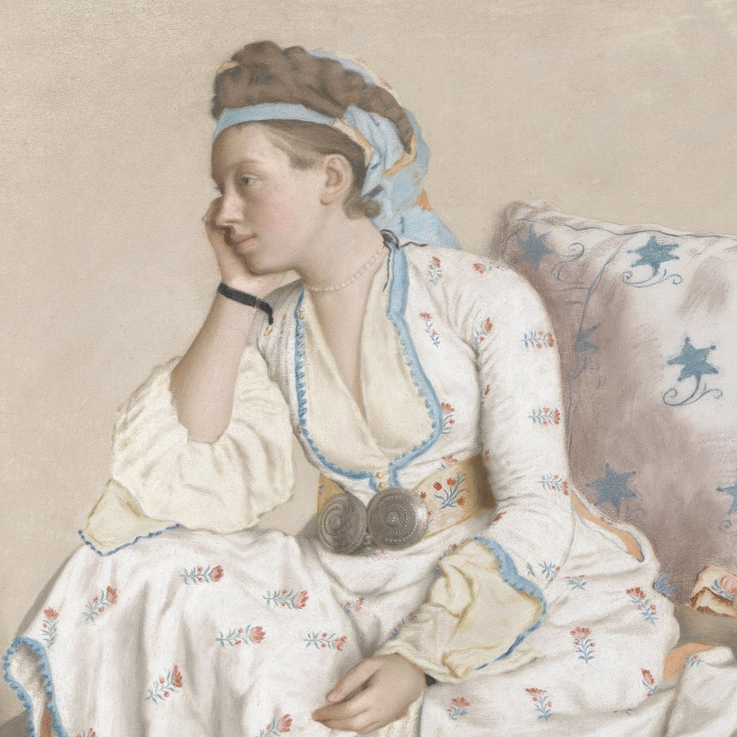 Marie Fargues, the Painter’s Wife by Jean-Etienne Liotard, portrays a young woman in a traditional dress with floral patterns, sitting pensively with her head resting on her hand. She is adorned with a headscarf and a pearl necklace, accented by two metallic discs around her neck. Reminiscent of Liotard's artwork, she sits on a cushioned seat embellished with blue floral designs.