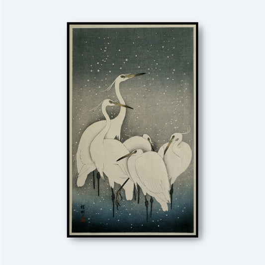 A framed painting, reminiscent of a vintage Japanese print titled "Group of Egrets by Ohara Koson," depicts a group of white herons standing closely together against a dark, starry background. Snowflakes fall gently around them, accentuating the tranquil and serene scene in traditional Japanese art style.