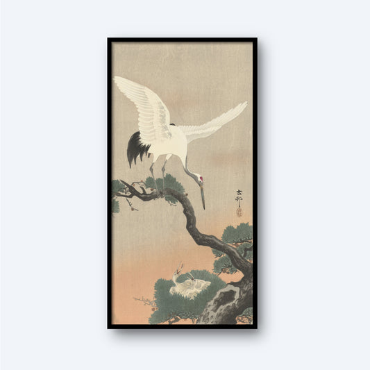 The framed print "Crane on Branch of Pine" by Ohara Koson showcases a white crane with outstretched wings perched on a pine branch, with another crane resting below amid pine needles. The background is rendered in a soothing gradient of soft, muted earth tones and features Japanese characters inscribed on the right side.