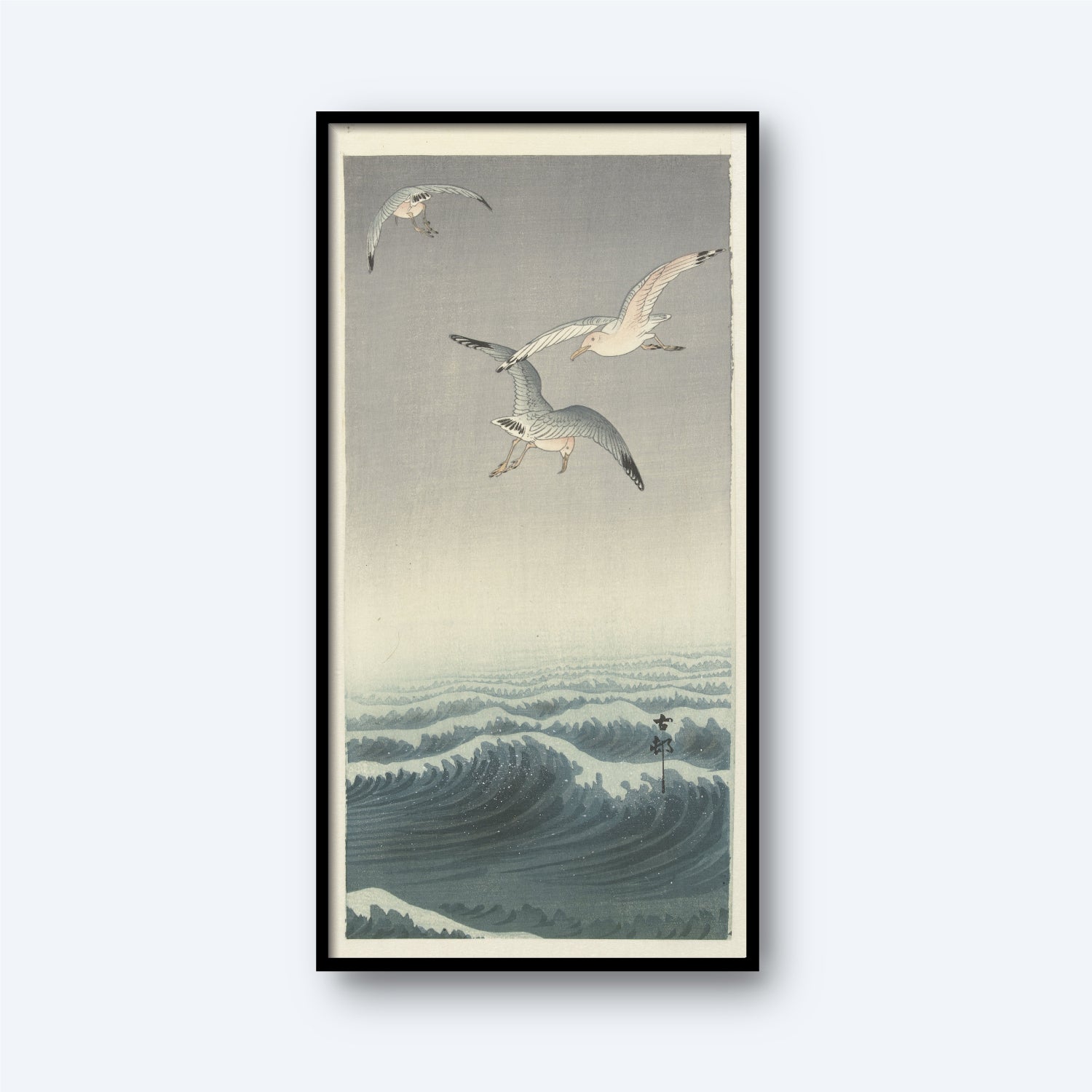 A framed "Three Seagulls by Ohara Koson | Vintage Japanese Woodblock Print" features three seagulls soaring above a turbulent ocean with rolling waves. The scene is illustrated in a traditional Japanese ukiyo-e style, reminiscent of Ohara Koson's work, with soft hues of blue and gray dominating the composition.